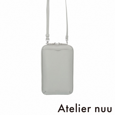 一款由 Atelier nuu 推出的灰色皮革隨身手機包，呈現長方形簡約造型，正面配有開口式插袋，並附有細長的可調節肩背帶，包體邊緣細膩，整體設計優雅且具有質感。