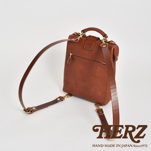 職人手作迷你軟皮杜勒斯包，採用溫暖的棕色皮革製成，配有可調節的肩帶和黃銅金屬配件，展現精緻工藝。