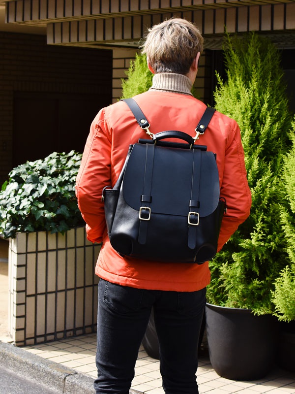 黑色皮革後背包，配有兩個金色方形扣環和黑色皮革肩帶。