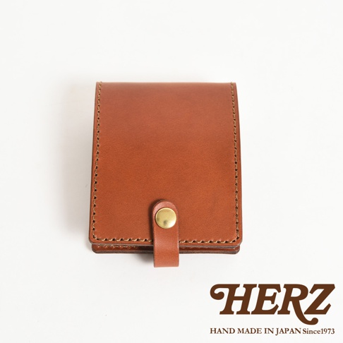 職人手作皮革便利貼收納套，呈現經典棕色調，使用高品質皮革製作，邊緣有細膩的縫線，正面中央有一個金屬按扣，方便開合。