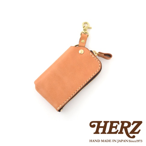 淺棕色職人手作皮革鑰匙包，附有拉鍊開合、皮革拉頭、金屬掛鉤及固定釦。