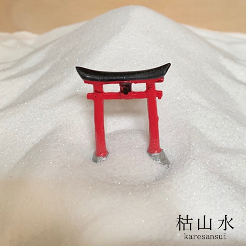 日本枯山水模型，紅色鳥居，黑色屋頂，底部有銀色細節，立於細緻的白色砂石中。