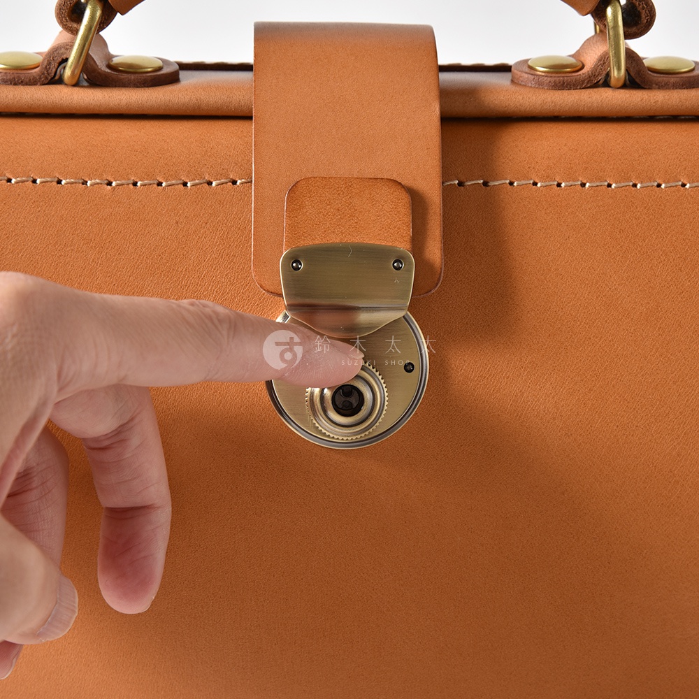 職人手作皮革軟式杜勒斯三用背包，展示卡其色皮革主體，搭配黃銅色金屬鎖扣，以及細緻的縫線細節。
