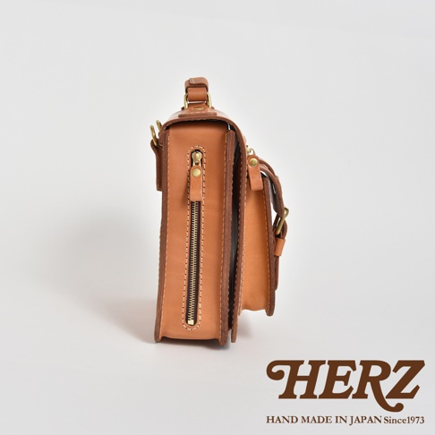 職人手作的淺棕色皮革立體口袋兩用單肩包，側面有拉鍊開合，搭配金色五金配件。