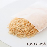 淺色無紡布包內裝有大量淡黃色、細碎的檜木屑，部分木屑散落在白色盤子上。