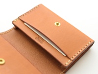 職人手作皮革名片收納夾，壓扣版 (KV-24) N，採用淺棕色牛皮製成，表面壓印品牌標誌。名片夾內層有卡槽，並以同色系縫線手工縫製，設有金色壓扣。