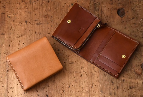 職人手作皮革直式卡片收納雙折短夾，一個為閉合的淺棕色皮革短夾，另一個為展開的深棕色皮革短夾，內有卡片槽、拉鍊零錢袋及按扣。