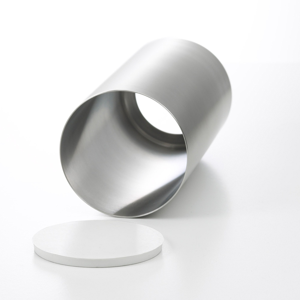 日製不鏽鋼圓筒形筷桶，表面光滑，呈現銀灰色金屬光澤，一旁擺放著一個白色圓形底蓋。