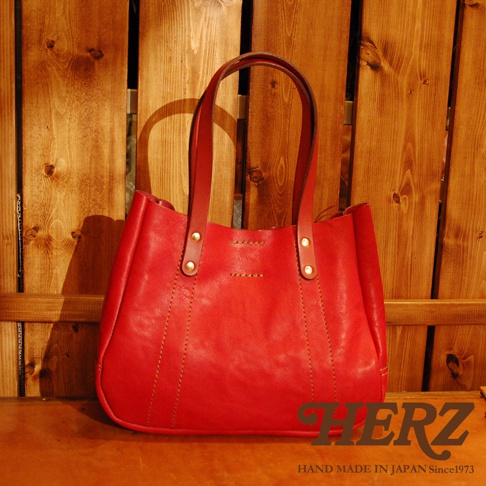 紅色皮革托特包，配有兩條皮革提把，包身有縫線裝飾，經典簡約設計。