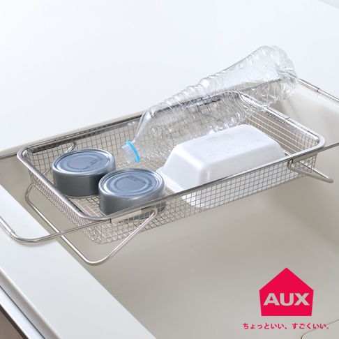 不鏽鋼網狀伸縮瀝水籃，籃內放置兩個灰色罐頭、一個白色長方形盒及一瓶透明塑膠瓶裝水。