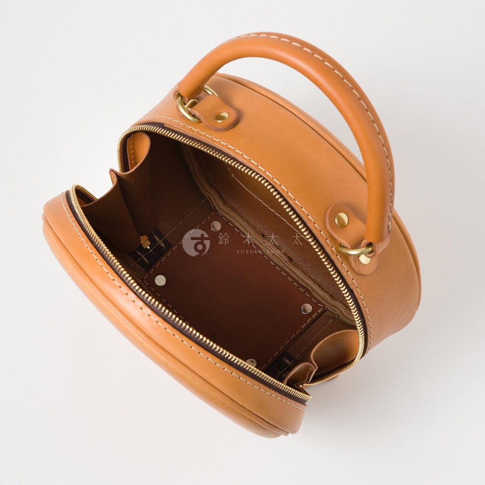 日本HERZ 職人手作皮革兩用圓形包 Q-13，復古棕色軟皮革材質，以圓筒形設計搭配上方提把，內部結構一覽無遺，拉鍊開口露出精緻縫線和品牌標記。