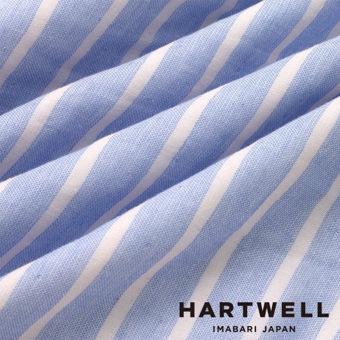 這張圖片展示了 HARTWELL 今治純棉材質的藍白條紋布料，呈現出柔軟且充滿皺褶的質感，畫面右下角印有黑色的 HARTWELL IMABARI JAPAN 品牌標誌。