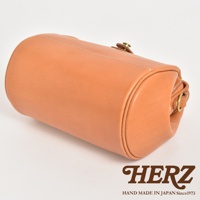 淺棕色皮革製成的圓筒形單肩包，帶有縫線細節和金屬扣環。