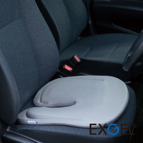 灰色U字型汽車坐墊，材質為透氣網布，置於汽車座椅上，Seat belt 扣帶可見。