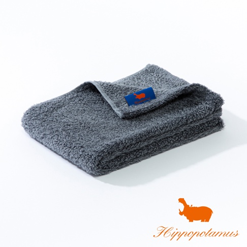一條深灰色竹棉混紡長毛巾，質地厚實柔軟，帶有藍色標籤，上面有橘色河馬圖案和品牌名稱。