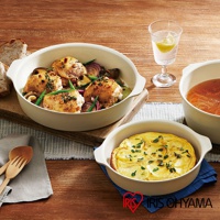 一組乳白色可拆式陶瓷不沾平底鍋，其中一個鍋內盛有烤雞和蔬菜，另一鍋內有馬鈴薯烘蛋，桌上還有玻璃杯和木製餐具。