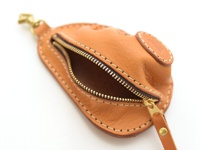一個由棕色皮革製成的餃子造型零錢包，配有金色拉鍊和黃銅掛鉤，手工縫製，細節精緻。