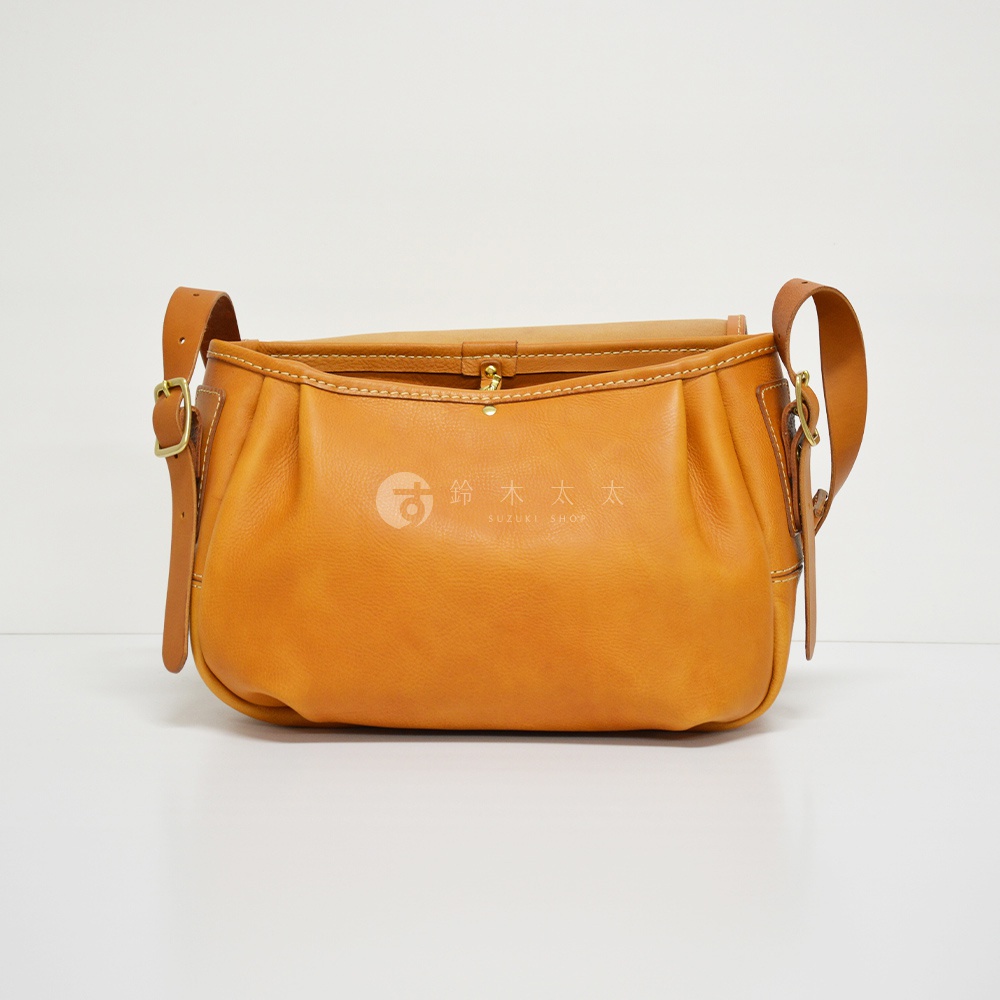 職人手作皮革復古翻蓋郵差包，採用溫暖的淺棕色皮革，帶有經典翻蓋設計和可調節的皮質肩帶，包身有細膩的縫線工藝。