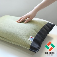 淺綠色藺草枕頭，表面織紋細緻，側邊為深灰色條紋布料，右下角有「made in Japan」標籤及品牌Logo。