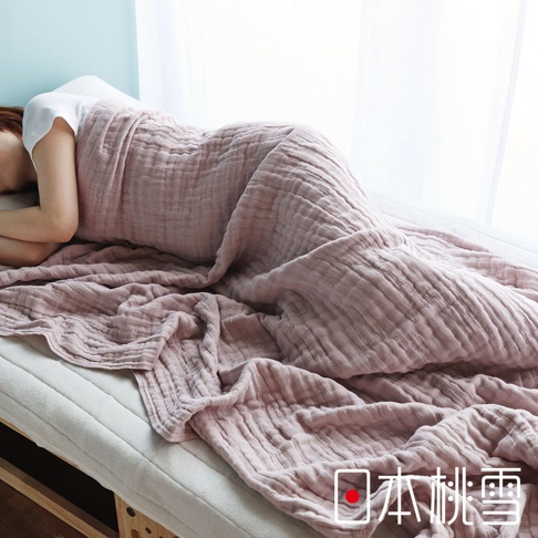 一個人在粉紅色五層紗被子下睡覺，被子鋪在白色床墊上。