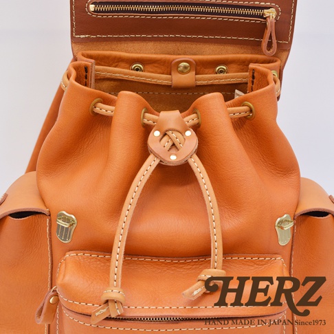 職人手作皮革復古風旅行後背包，採用天然棕色皮革，配有抽繩束口、金屬扣飾和縫線細節。