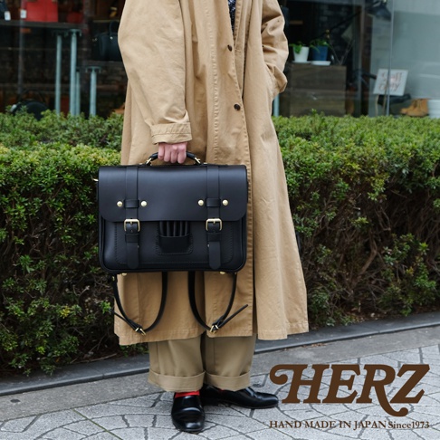 黑色皮革三用學生包，帶有金色扣環和可調節皮帶，可肩背或後背，呈現傳統歐風設計。