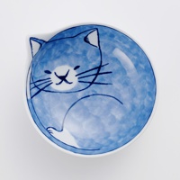 陶瓷貓咪飯碗，藍白色調，碗內繪有簡約風格的藍色小貓圖案，貓咪臉部表情可愛，身體蜷縮，碗邊緣為貓耳朵造型。