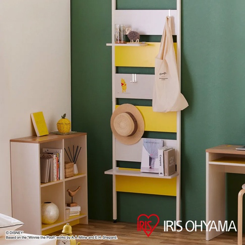 白色木質頂天立地收納架，點綴黃色層板，掛有米色帆布袋，架上擺放裝飾品、帽子、書籍。