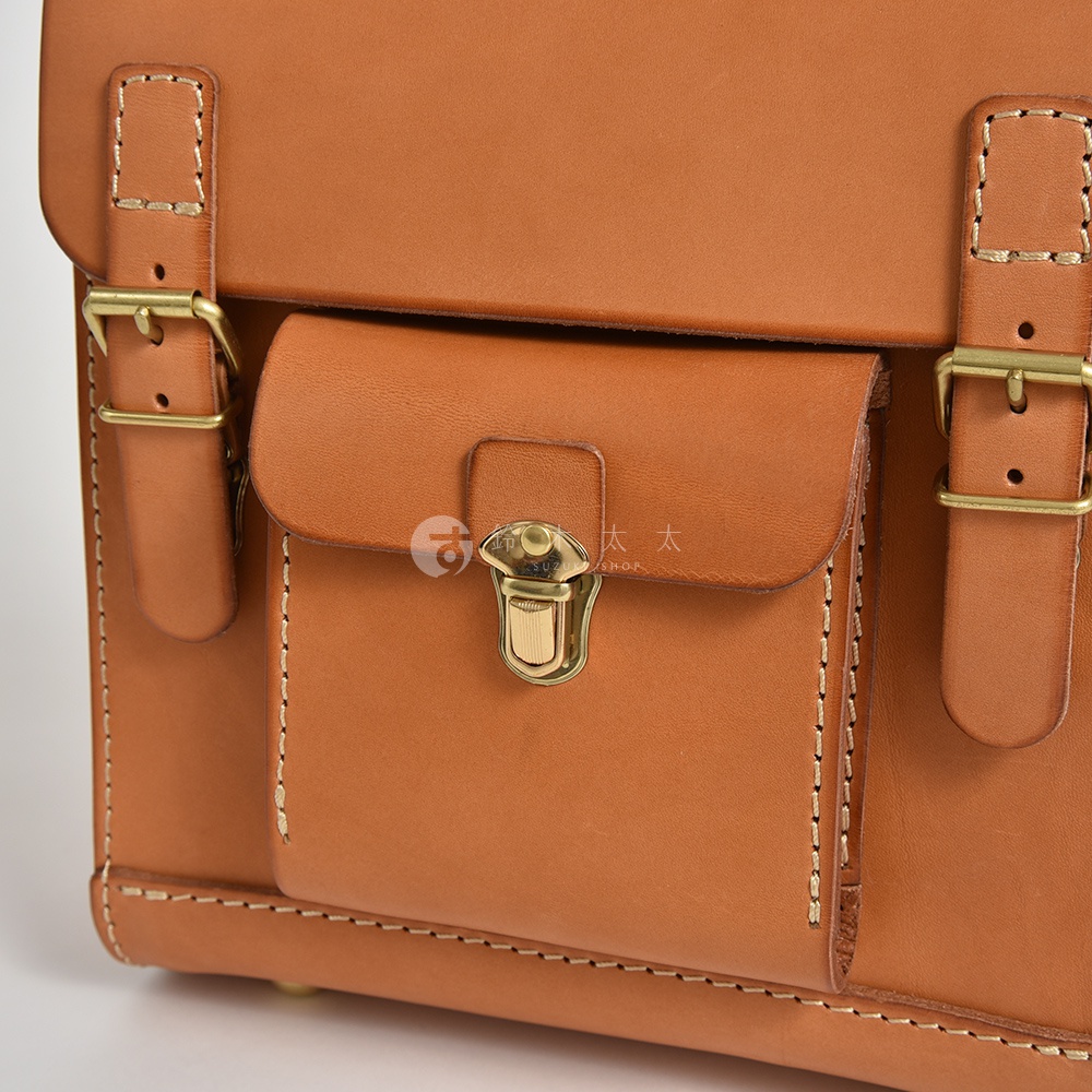 職人手作皮革經典學院風迷你後背包，採用棕色皮革材質，配有金屬釦環和鎖扣，展現精緻工藝與復古風格。