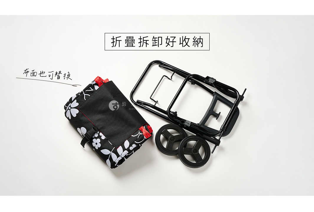黑色輕量折疊購物車，配有黑色框架和兩個黑色輪子。購物車帶有一個可拆卸的黑色布袋，上面印有白色花朵圖案和紅色滾邊。
