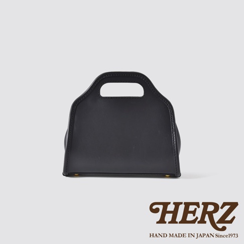 黑色皮革單肩兩用拱型手袋，設有手提握把，底部有金屬腳釘。