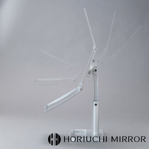 銀色金屬材質的桌上型化妝鏡，具有可三折的鏡臂，能調整不同角度，鏡面為長方形。