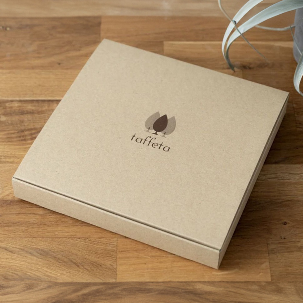楓木紋理的紙盒，盒蓋中央印有「taffeta」品牌名稱與樹葉圖案。