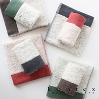 四條斜紋圖案今治長纖有機棉毛巾，分別為紅、綠、粉紅、深藍色調，搭配白色毛巾主體，質地柔軟。