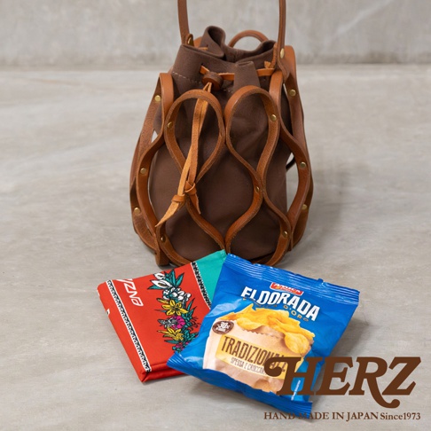日本HERZ職人手作皮革Organ編織水桶包，搭配零食與花卉圖案的物品。