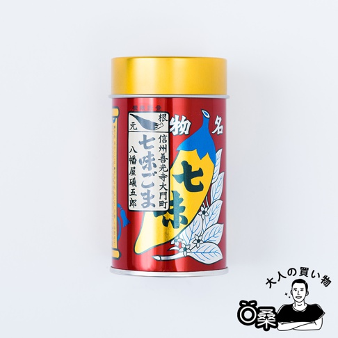 紅色金頂的罐裝唐辛子七味粉，罐身印有黃色七味辣椒圖案，並有日文標示「七味ごま」、「信州善光寺大門町」等字樣。