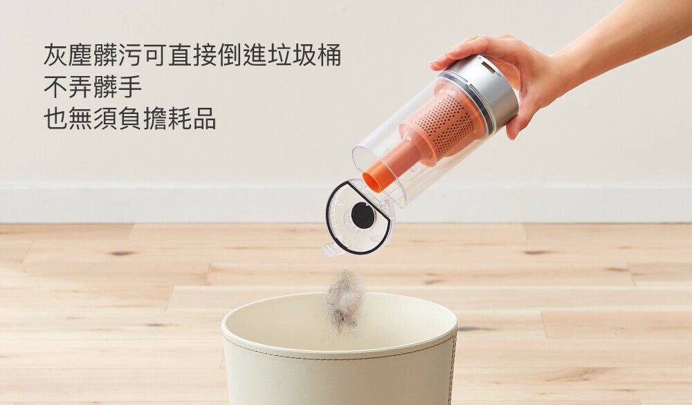 手持無線吸塵器集塵筒，透明塑膠材質，內有橘色濾網，正由手傾倒灰塵進入淺米色垃圾桶。