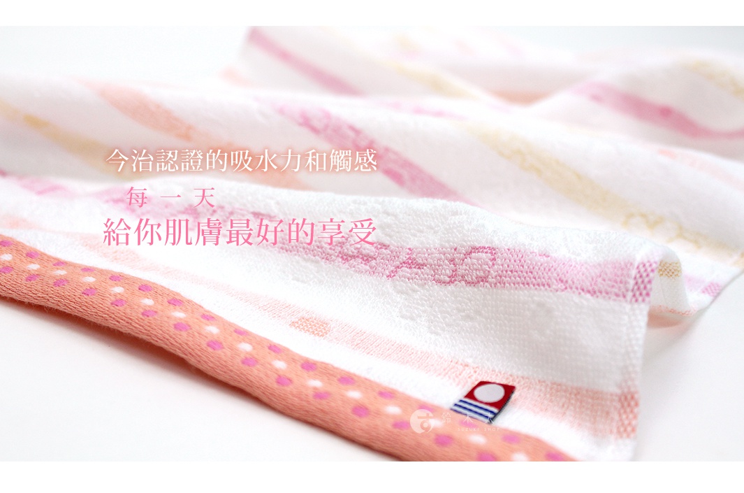 一條今治小花浴巾，以粉色、淡黃色與白色條紋交織，邊緣飾有粉色圓點圖案。材質柔軟，觸感細緻。
