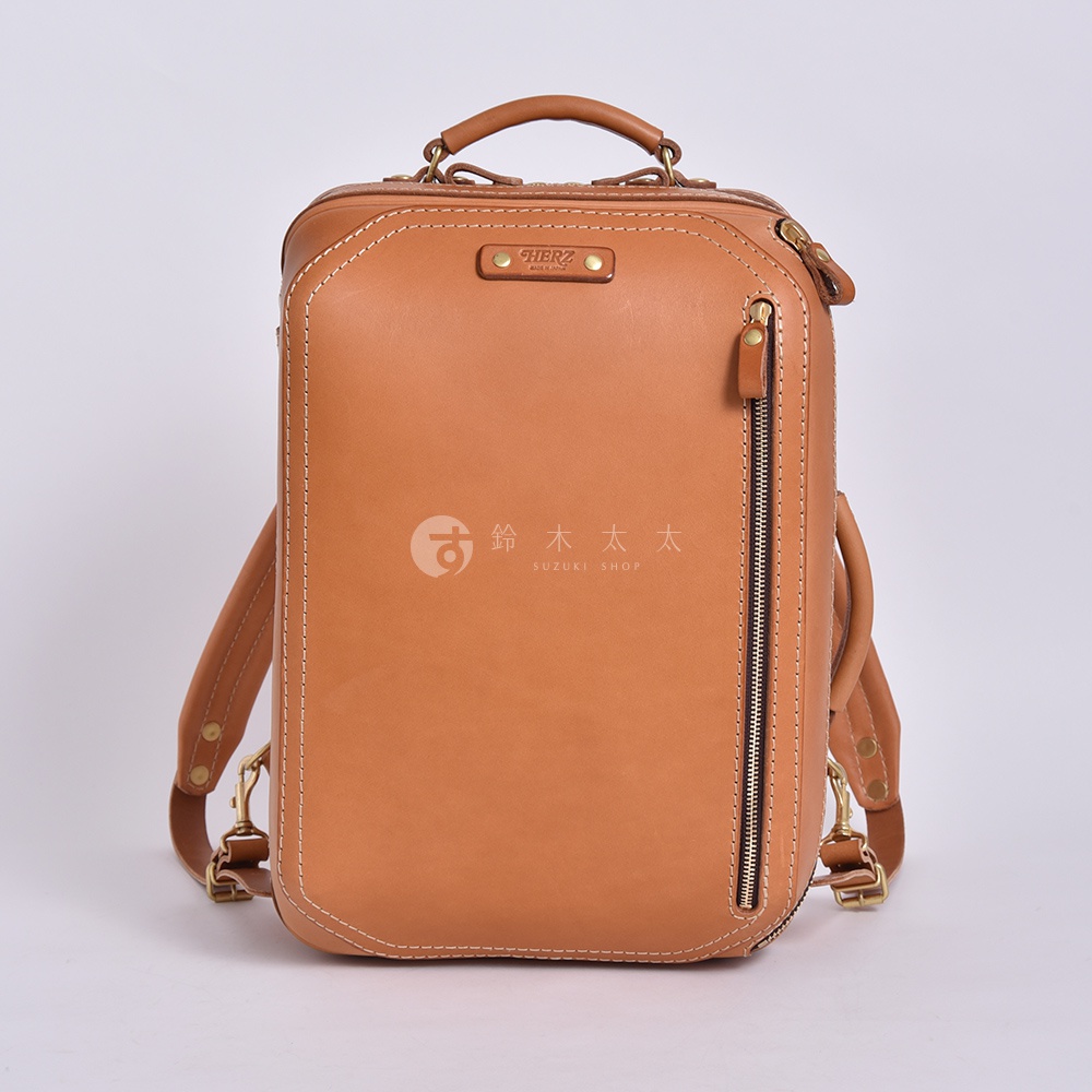 職人手作皮革兩用商務後背包 R-33，以淺棕色皮革製成，搭配白色縫線和金色拉鍊。包身方正，頂部設有提把，兩側有可拆卸的皮革揹帶，適合商務或日常使用。