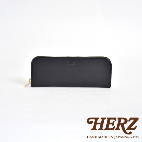 黑色皮革長款筆袋，正面有壓印品牌標誌，側邊有金色拉鍊。