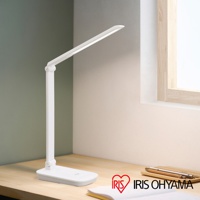 白色LED檯燈，可折疊設計，具有無線充電功能，放置於木質桌面，背景有窗戶和綠色牆面。