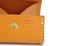 職人手作皮革箱型收納零錢包 (KK-23)，採用天然皮革材質，呈現溫潤的棕褐色調。錢包表面設有金屬按扣，並壓印有「HERZ MADE IN JAPAN」字樣，側邊縫線精緻。