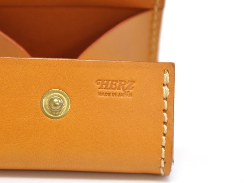職人手作皮革箱型收納零錢包 (KK-23)，採用天然皮革材質，呈現溫潤的棕褐色調。錢包表面設有金屬按扣，並壓印有「HERZ MADE IN JAPAN」字樣，側邊縫線精緻。