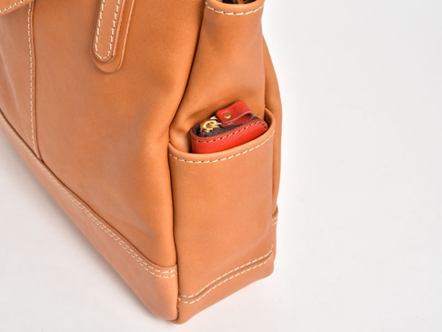 職人手作皮革直式肩背托特包 (T-32-T)，淺棕色皮革，側邊置物袋裝有紅色零錢包，縫線清晰。