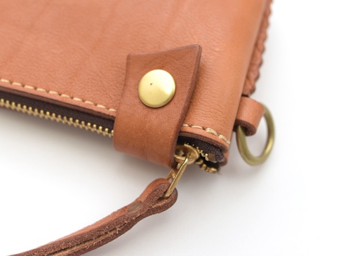 棕色皮革短夾，配有黃銅色拉鍊、按扣及掛環，縫線細緻，整體呈現自然皮革紋理。