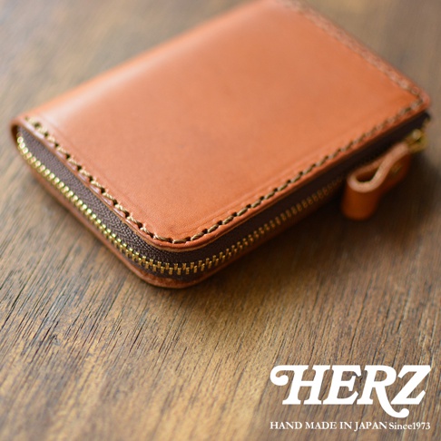 職人手作的棕色皮革拉鍊短夾，拉鍊為金色，邊緣有縫線裝飾。