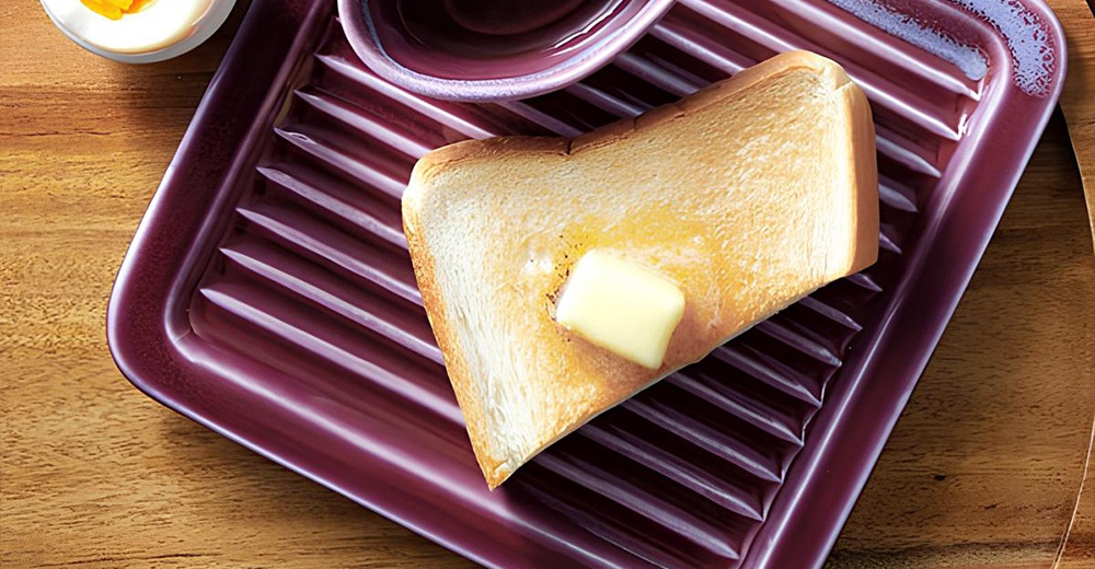 深紫色美濃燒素釉吐司酥脆專用盤，盤面有條紋設計，盤中擺放著一片塗有奶油的烤吐司。