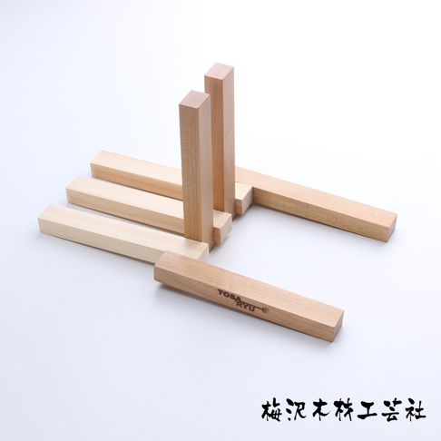 淺色木製翻轉隔熱墊，由多塊方形木條組成，部分木條帶有刻字。