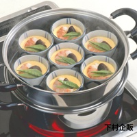 不鏽鋼雙層蒸氣料理鍋，內置七個裝有蒸蛋、蝦仁、香菇及豌豆的日式小碗，碗內有藍色條紋裝飾，鍋身有黑色把手，鍋底加熱紅色光芒。