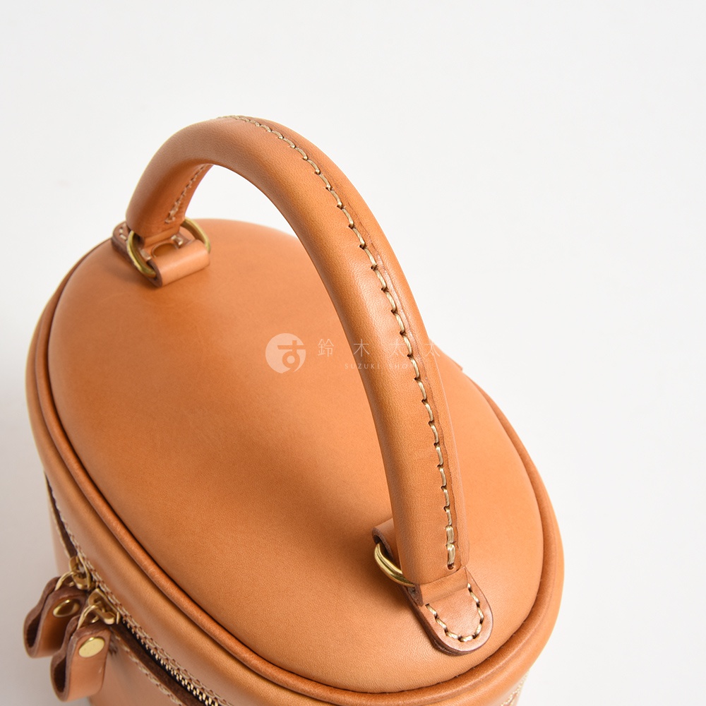 棕褐色皮革圓筒型化妝手提包，頂部有圓潤的提把，車縫線清晰，整體呈現簡約風格。